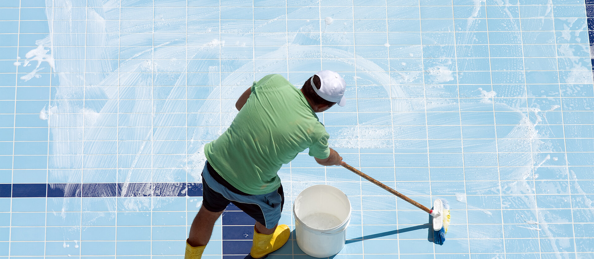 Photo of man washing a tile pool.